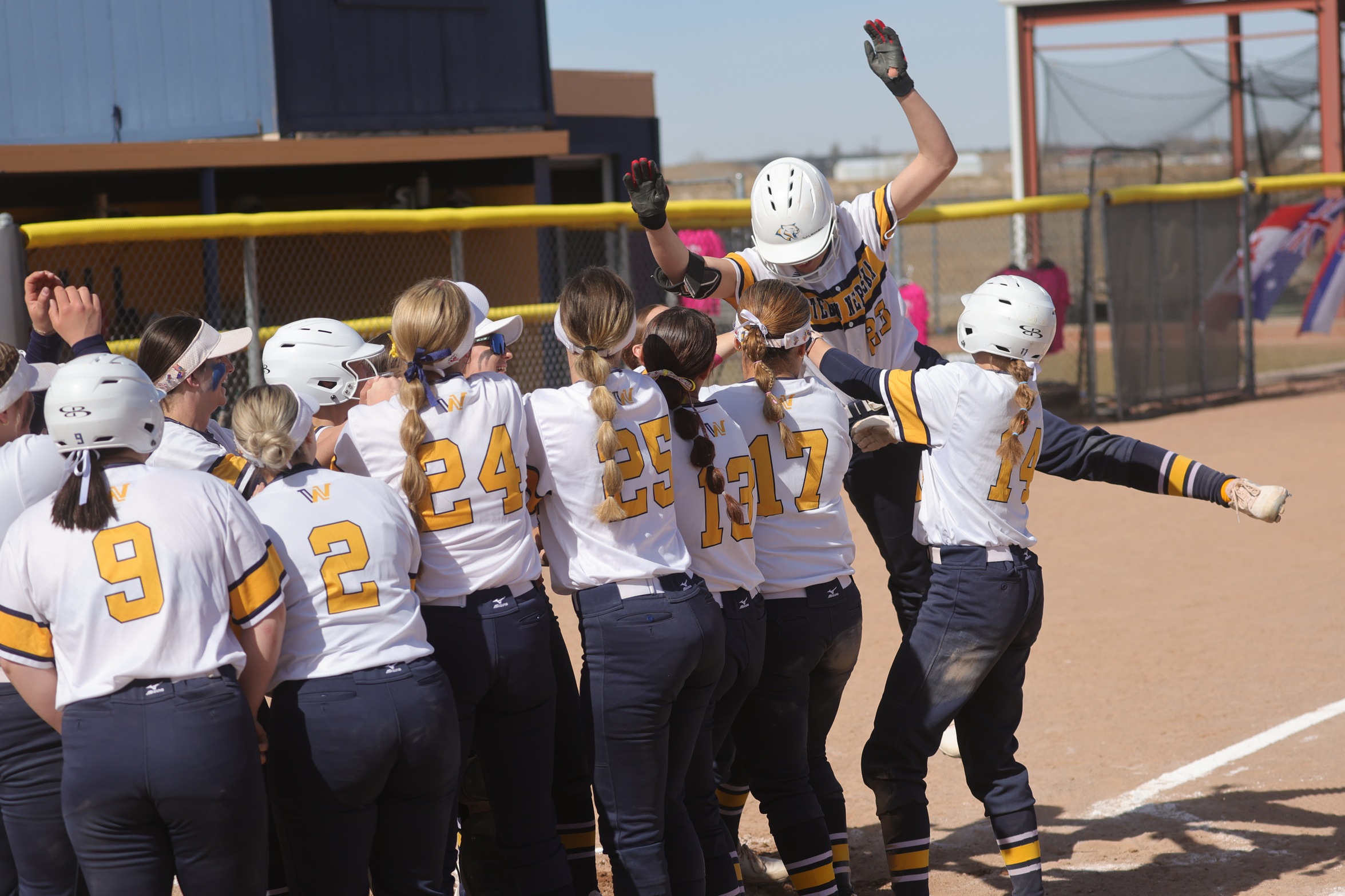 Abbey Arntsen gets tossed backwards after hitting a home run in the team's home run celebration in the first game of a doubleheader on Sunday.